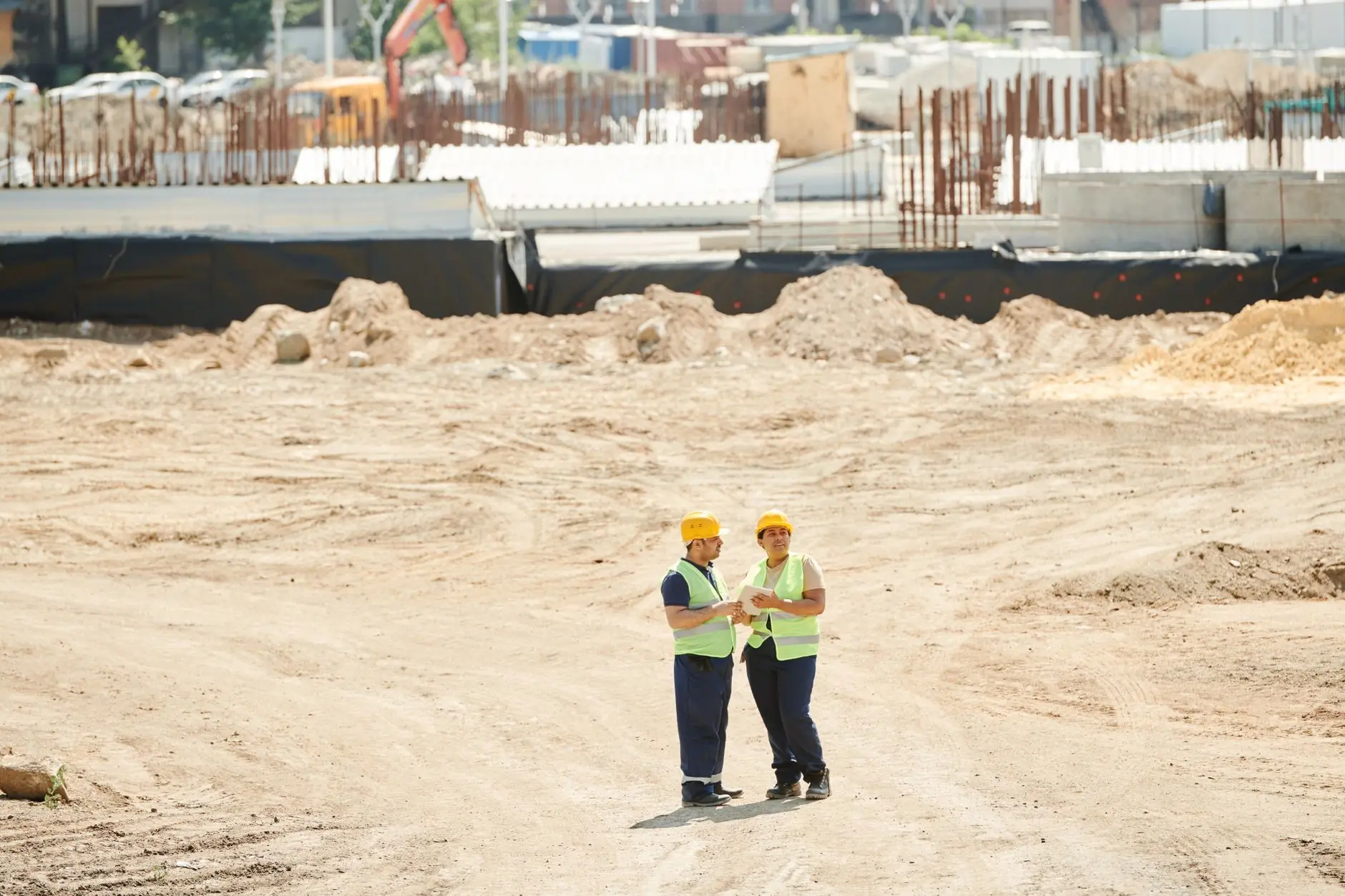 Two site supervisors in hard hats on a cleared project site