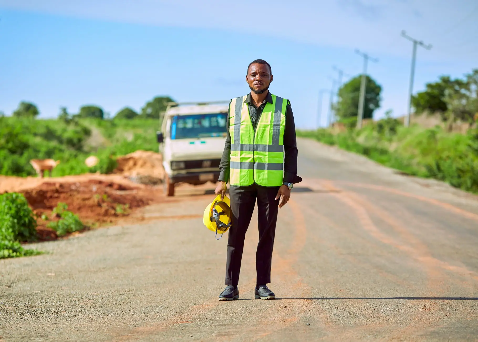 Site worker in a high-visibility vest holding a hard hat